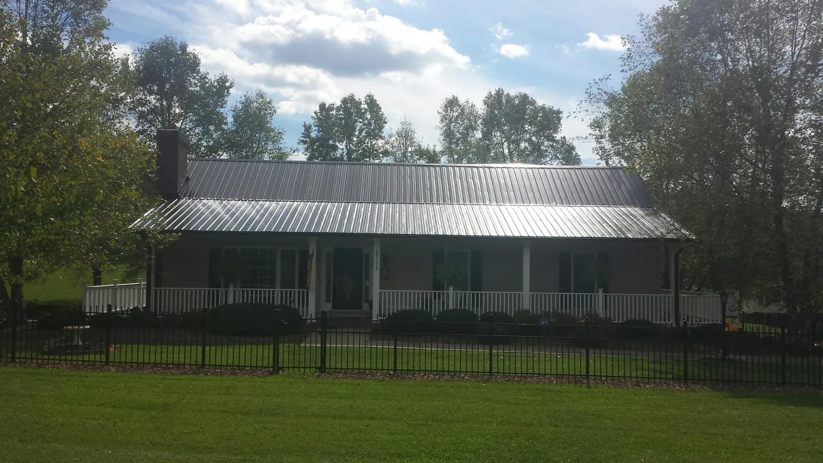 Gray metal roof on a brick ranch with a full width front porch — Gutter Guard Installation work by our crew in Hollsopple