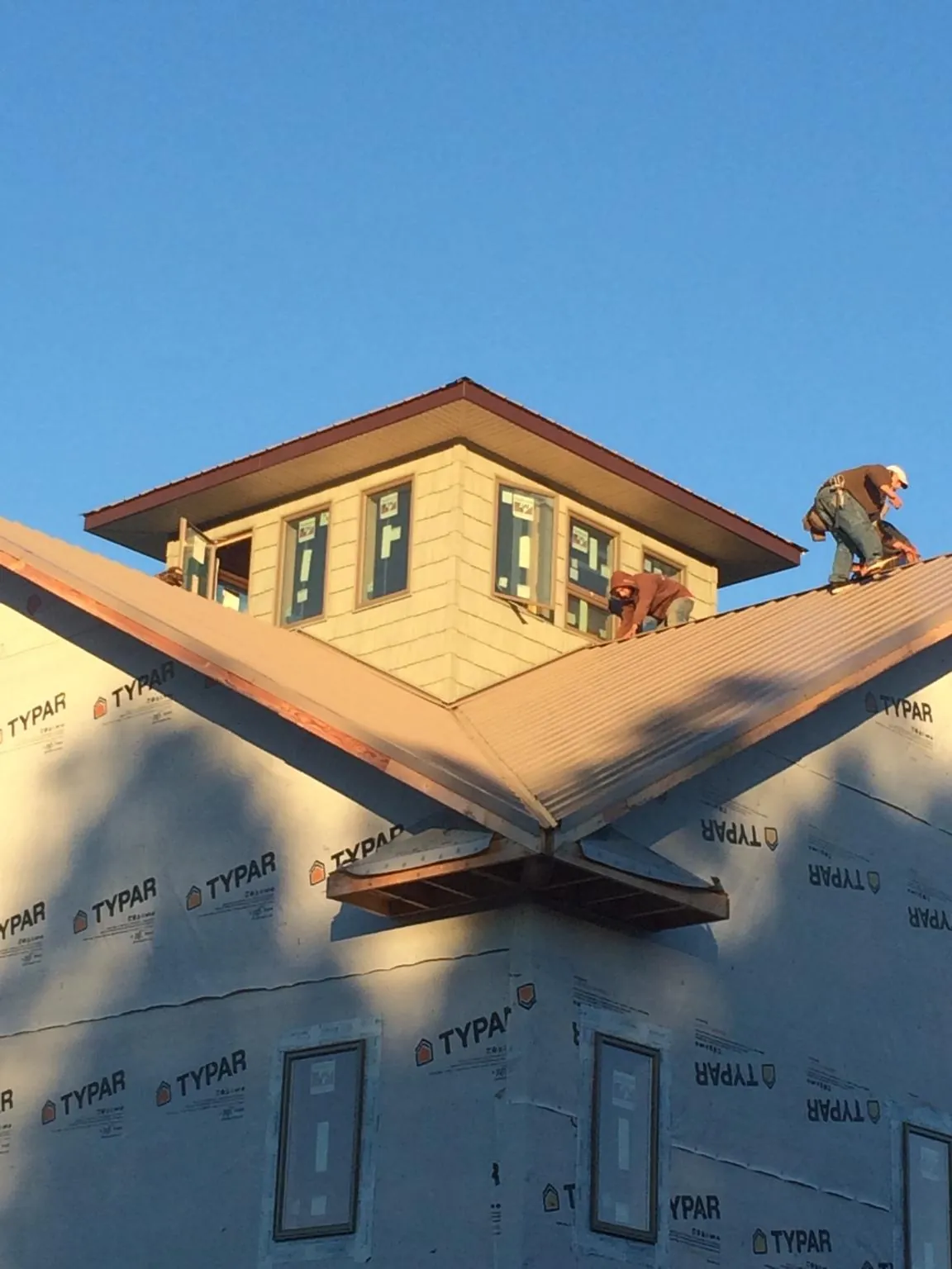 Roofers working around a rooftop cupola on a new metal roof at sunset — Roof Waterproofing in Hollsopple by Roofing Brothers